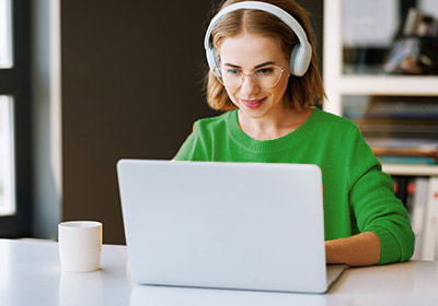 Frau mit grünem Shirt sitzt vor Laptop